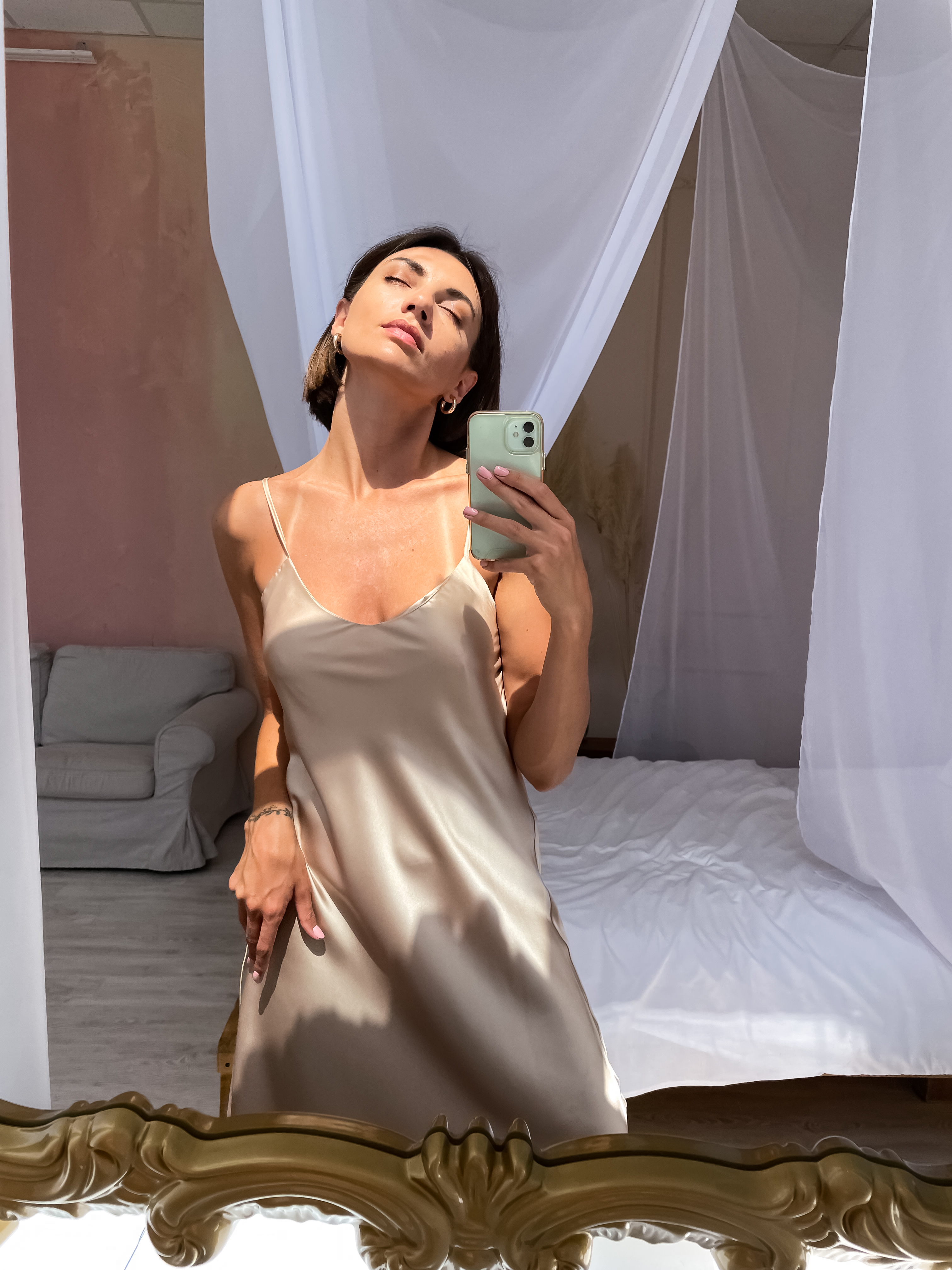 fit-tanned-woman-romantic-beige-silk-dress-home-takes-photo-selfie-phone-mirror.jpg